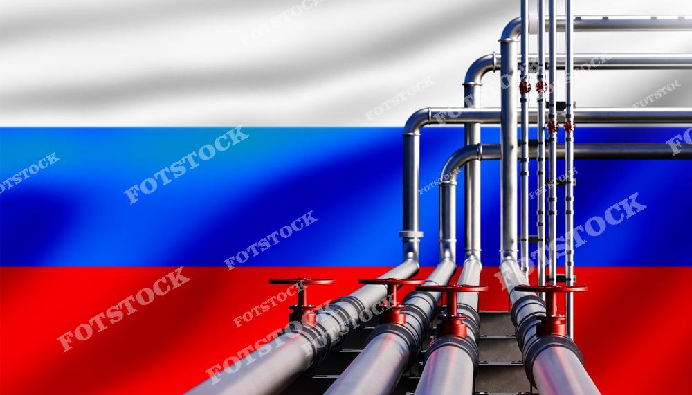 На изображении металлические трубы с запорными клапанами на фоне российского флага, символизирующие значимость газовой и нефтяной инфраструктуры России в сфере экспорта энергетических ресурсов.